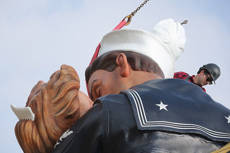 A worker prepares to place "Unconditional Surrender," a 25-foot cast-bronze sculpture in color of a sailor and a nurse in lip-locked embrace, outside the Caen Memorial in Normandy, France, in this 2014 file photo. 