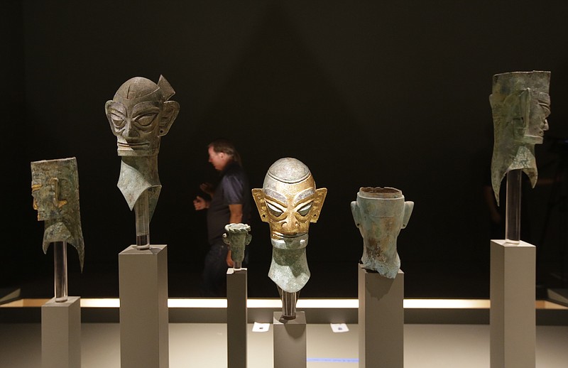 
              In this Thursday, Oct. 9, 2014 photo, a visitor to the Bowers Museum walks past a row of bronze masks, in Santa Ana, Calif. "China's Lost Civilization: The Mystery of Sanxingdui" includes more than 100 ancient pieces, some never seen outside China. The exhibit will remain at the Bowers until March 15, 2015, after which they will move to Houston's Museum of Natural Science. (AP Photo/Chris Carlson)
            