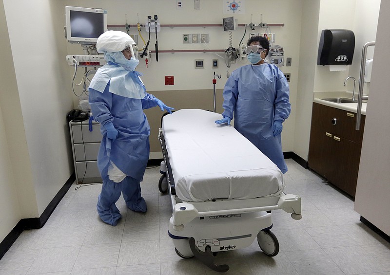 
              FILE - In this Oct. 8, 2014, file photo, Bellevue Hospital nurse Belkys Fortune, left, and Teressa Celia, Associate Director of Infection Prevention and Control, pose in protective suits in an isolation room, in the Emergency Room of the hospital, during a demonstration of procedures for possible Ebola patients in New York. A doctor who recently returned to New York City from West Africa is being tested for the Ebola virus. The doctor had a fever and gastrointestinal symptoms and was taken Thursday to Manhattan's Bellevue Hospital. (AP Photo/Richard Drew, File)
            