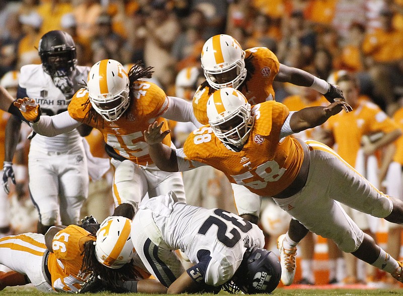 Tennessee defenders A.J. Johnson (45) Owen Williams (58) and Jalen Reeves-Maybin jump onto Utah State running back Joe Hill during their game on Aug. 31, 2014, at Neyland Stadium in Knoxville.