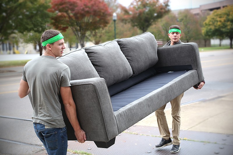 Bellhops Diego Meraz and Donald McDowell carry a couch into a Walnut Street apartment in downtown Chattanooga.