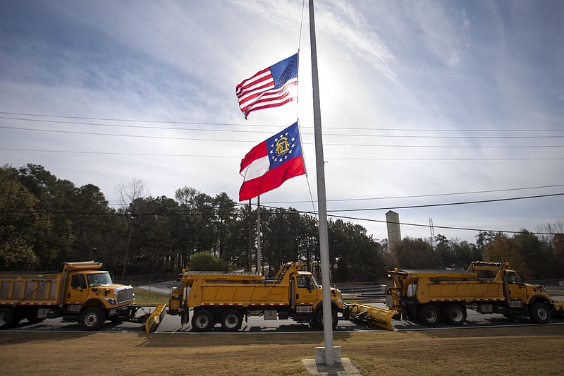 
              The American and Georgia state flags fly at half-staff to honor the passing of former Gov. Carl Sanders as snow plows line up outside the Georgia Department of Transportation's Maintenance Operations Facility during a statewide severe winter weather exercise, Tuesday, Nov. 18, 2014, in Atlanta. More than 600 participants from local and state government agencies, organizations and volunteer groups took part in the mock winter storm. Less than year after a snowstorm triggered an epic traffic jam that brought metro Atlanta to a halt, Georgia emergency management officials are highlighting what they'll do differently next time while acknowledging limitations in how they can respond to a major winter storm. (AP Photo/David Goldman)
            