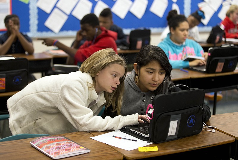 In this Nov. 20, 2014 photo, eighth-graders Alexis Gibbons, left, and Yocelin Rodriguez use a digital textbook to solve a math problem at Burney Harris Lyons Middle School in Athens, Ga. Georgia schools will use only digital textbooks within the next six years under a proposal one state lawmaker has planned for the 2015 session.