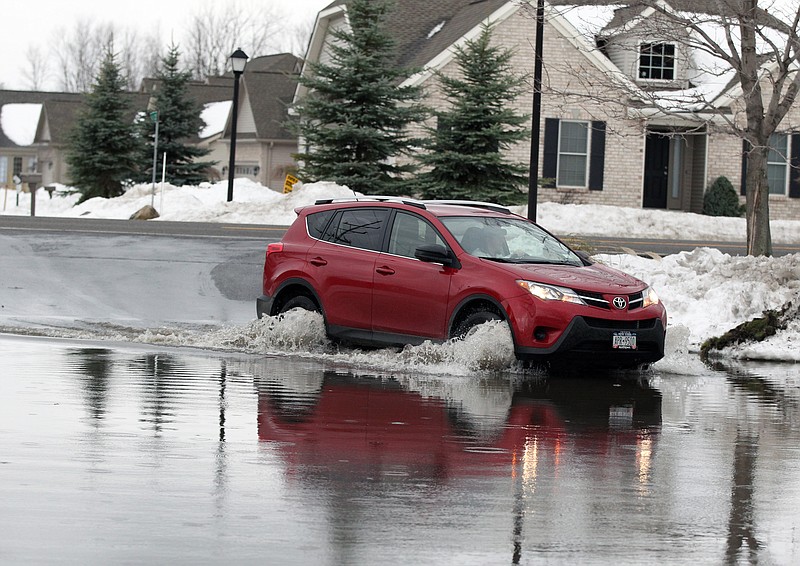 
              A resident of Bell Tower Condominium Apartments drives through water from a swollen Cayuga Creek as flooding from melting snow following last week's snowstorms are occurring on a minor scale, Monday, Nov. 24, 2014, in Lancaster, N.Y. (AP Photo/Gary Wiepert)
            