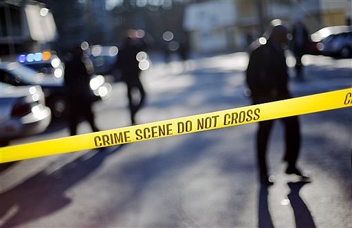 Crime scene tape blocks of the area of an apartment complex where authorities say two police officers were shot, leading to a neighborhood search for the suspected gunman, Friday, Dec. 12, 2014, in Decatur, Ga. DeKalb County police Capt. Stephen Fore says both officers suffered what are believed to be non-life threatening injuries. (AP Photo/David Goldman)