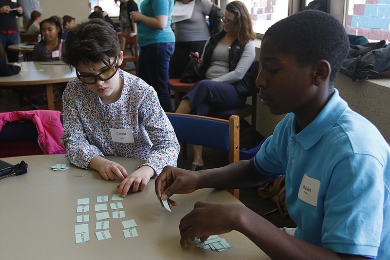 Carina Miller, left, and Melvin Tobar arrange sheets of paper for a game designed to teach the basics of a binary system at the Chattanooga Public Library's "Hour of Code" workshop on Saturday. The workshop taught elementary and middle school students fundamentals of coding and introduced them to computer science professionals.