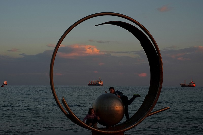 Children play on an art sculpture by the sea Sunday in southern port city of Limassol, Cyprus. Steady rain, overcast skies and unseasonably cold temperatures over the last 48 hours have resulted in more than twice the average monthly precipitation in the eastern Mediterranean island. (AP Photo/Petros Karadjias)