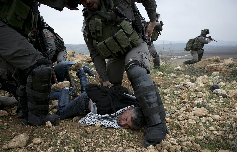 
              Israeli border police detain a Palestinian protester following a prayer for Palestinian Cabinet minister Ziad Abu Ain, who collapsed shortly after a protest on Dec. 10 in the West Bank village of Turmus Aya, as they clash with the troops near the village outside of Ramallah, Friday, Dec. 19, 2014. Clashes erupted between Palestinian protesters and Israeli forces at a West Bank military checkpoint near Turmus Aya, where Abu Ain collapsed and later died en route to hospital. Palestinian and Israeli pathologists subsequently disagreed over the cause of Abu Ain's death. The Palestinian expert said the cause of death was a "blow," while his Israeli colleague said Abu Ain died of a heart attack. (AP Photo/Majdi Mohammed)
            