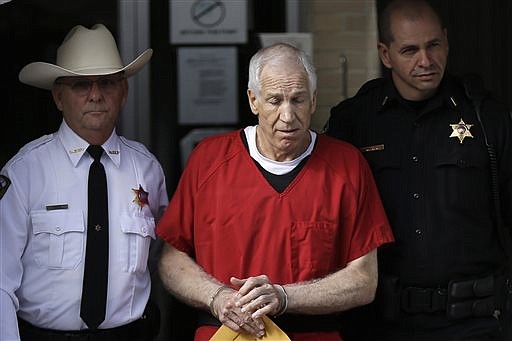FILE - In this Oct. 9, 2012, file photo, former Penn State University assistant football coach Jerry Sandusky, center, is taken from the Centre County Courthouse by Centre County Sheriff Denny Nau, left, and a deputy, after being sentenced in Bellefonte, Pa. Sandusky lost a legal battle to restore his $4,900-a-month pension, a benefit that was canceled two years ago after he was sentenced for child molestation. (AP Photo/Matt Rourke, File)