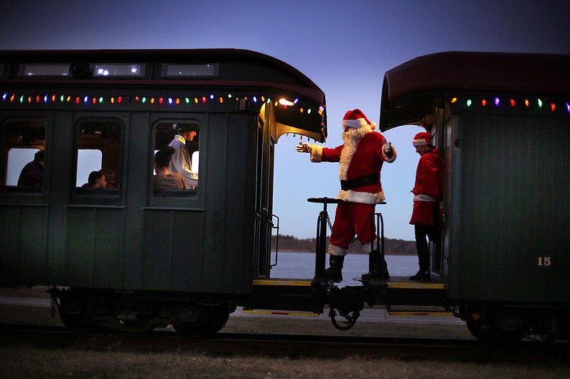 A man portraying Santa Claus moves between cars while greeting passengers during a Polar Express holiday train ride to the "North Pole" on the Maine Narrow Gauge Railroad in Portland, Maine. The Polar Express is the largest annual fundraiser for the railroad's museum.