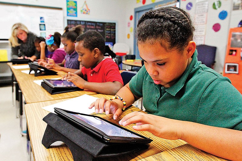 Mishayla Greene, a Woodmore Elementary student, right, works on an iPad that her class received from the Rotary Club.