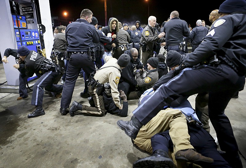 Police try to control a crowd Wednesday, Dec. 24, 2014, on the lot of a gas station following a shooting Tuesday in Berkeley, Mo. St. Louis County police say a man who pulled a gun and pointed it at an officer has been killed. 