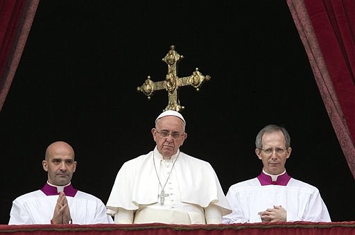 Pope Francis, center, delivers his "Urbi et Orbi" (to the city and to the world) blessing from the central balcony of St. Peter's Basilica at the Vatican, Thursday, Dec. 25, 2014. 