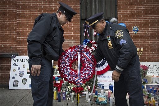 Members of the New Rochelle, N.Y. police department place a wreath in this Dec. .22, 2014, photo at a makeshift memorial near the site where NYPD officers Rafael Ramos and Wenjian Liu were murdered in New York.