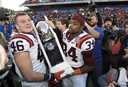 Virginia Tech place kicker Joey Slye (46) and running back Kyshoen Jarrett (34) hold the trophy after they beat Cincinnati in the Military Bowl on Dec. 27, 2014, in Annapolis, Md. Virginia Tech won 33-17.