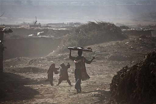 A Pakistani sweet vendor walks by Afghan refugee girls as they get embroiled in a sandstrom on the outskirts of Islamabad, Pakistan, on Dec. 26, 2014.