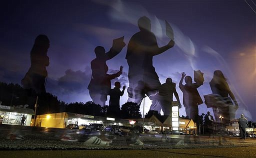 Protesters march in the street as lightning flashes in the distance in Ferguson, Mo., in this Aug. 20, 2014 file photo.