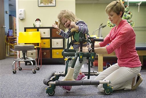 Physical therapist Daphne Wallace, right, works with three-year-old Carly Chandler on a Gate Trainer machine to help with strengthening of muscles and walking, in Hoover, Ala., in this Dec. 22, 2014 photo.