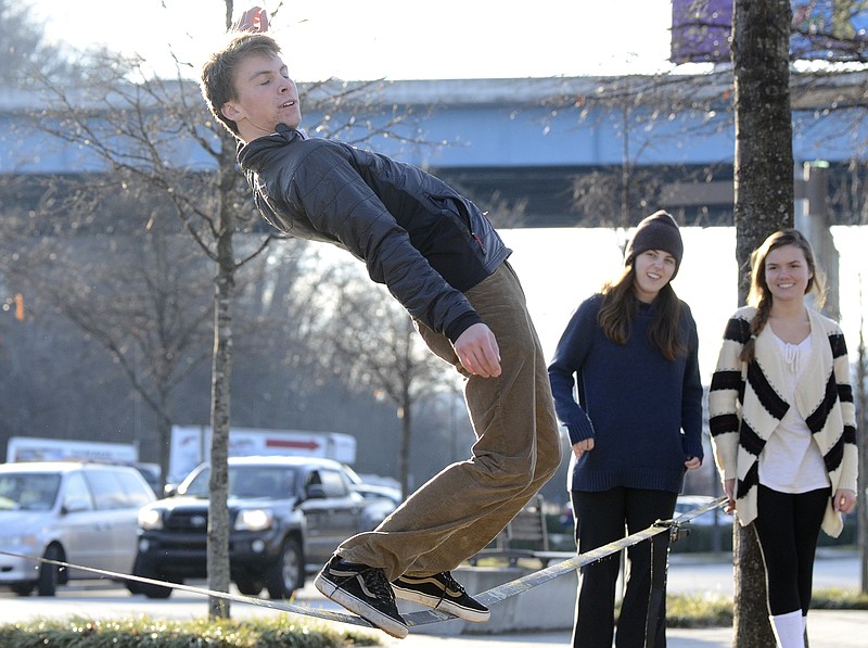 Roy Tyson attempts to keep his balance shortly before falling off a slackline while Maggie Swafford, left and Emma Gibson watch next to Riverside Drive in Chattanooga, Tenn.
