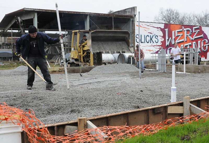 GNS Plumbing's Jesus Sarabia uses a transit to level gravel at Slick's Burgers on Main Street.