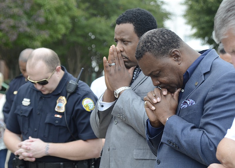 Pastor Ternae Jordan Sr., Pastor Kevin Adams and Investigator Curtis Penney, from right, pray as law enforcement officers gather with clergy and community members to pray for a stop to violence in this Oct. 28, 2014, file photo.