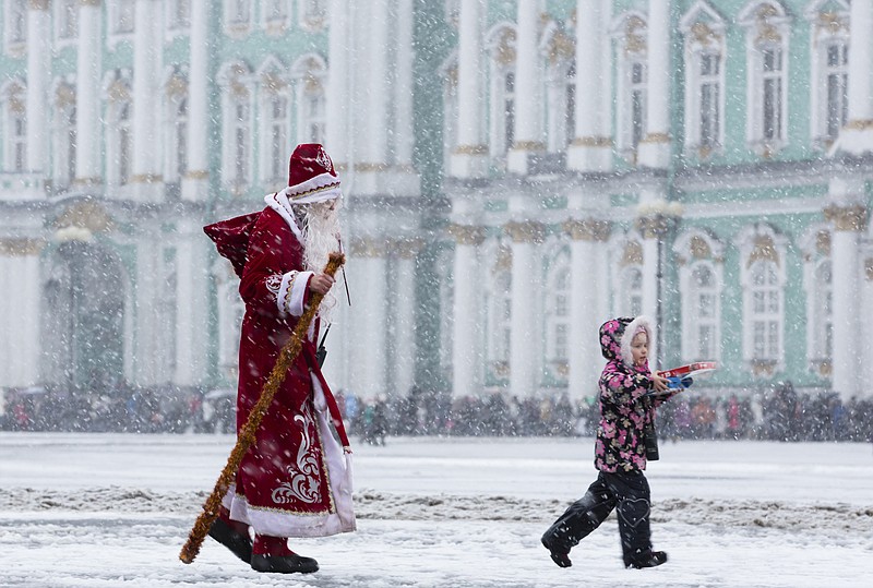 A man wearing a Ded Moroz (Grandfather Frost) costume walks in snowfall at Dvortsovaya Square in St. Petersburg, Russia, Saturday, Jan. 3, 2015.
