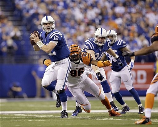 Indianapolis Colts quarterback Andrew Luck, left, prepares to throw a 36-yard touchdown pass as he is grabbed by Cincinnati Bengals' Carlos Dunlap (96) during their NFL wildcard playoff ame Sunday, Jan. 4, 2015, in Indianapolis. 