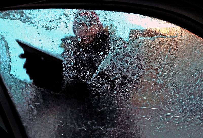 Marianna Cymbala fights to scrape the ice off her windows as sleet and freezing rain fall in St. Louis on Monday, Dec. 1, 2014. 