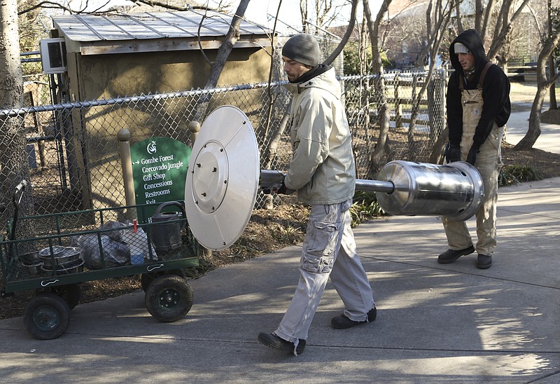 Geoff Downey, left, and Jared Schoolcraft carry a heater to the work site where they are putting a roof on the owl
enclosure as temperatures hover near 12 degrees at the Chattanooga Zoo on Thursday.