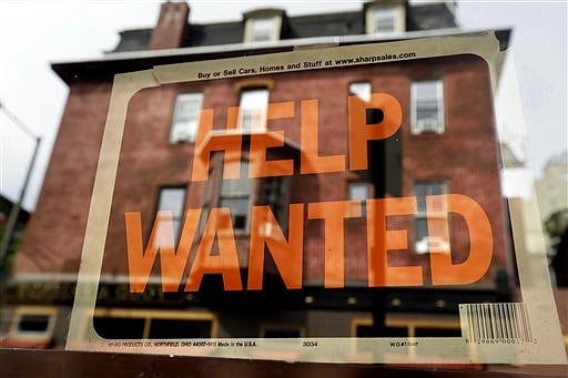 A Philadelphia business displays a help wanted sign in its storefront in this 2013 file photo. With the price of oil below $50 a barrel, consumers will have steadily more money to spend, potentially creating job openings at retailers, auto dealers, shipping firms, restaurants and hotels.