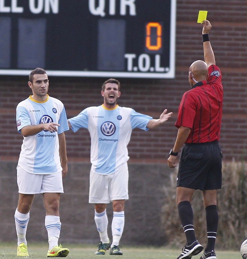 CFC's Niall McCabe, center, reacts as the referee yellow cards teammate Thibault Charmey, left, during Chattanooga's regional final soccer match against the Tulsa Athletics on July 19, 2014, in Chattanooga.