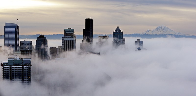 Downtown buildings rise above a low-level morning fog as Mount Rainier is seen some 80 miles distant Friday, Jan. 9, 2015, in this view from atop the Space Needle in Seattle. 