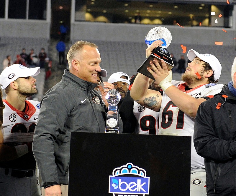 Georgia center David Andrews, shown here holding up the Belk Bowl trophy late last month alongside coach Mark Richt, expects a future in football but does not know in what capacity. (UGA Photo by John Kelley)