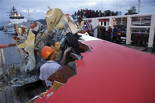 Members of the National Transportation Safety Board inspect the portion of the crashed AirAsia Flight 8501 on the deck of rescue ship Crest Onyx at Kumai port in Pangkalan Bun, Indonesia, Sunday, Jan. 11, 2015. A day after the tail of the crashed AirAsia plane was fished out of the Java Sea, the search for the missing black boxes intensified Sunday with more pings heard. 