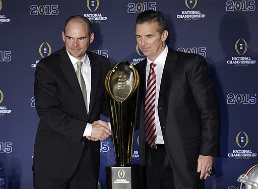 Ohio State head coach Urban Meyer, right, and Oregon head coach Mark Helfrich pose with the championship trophy after a news conference before the NCAA college football playoff championship game on Jan. 11, 2015, in Dallas. Oregon plays Ohio State in the championship game on Monday.