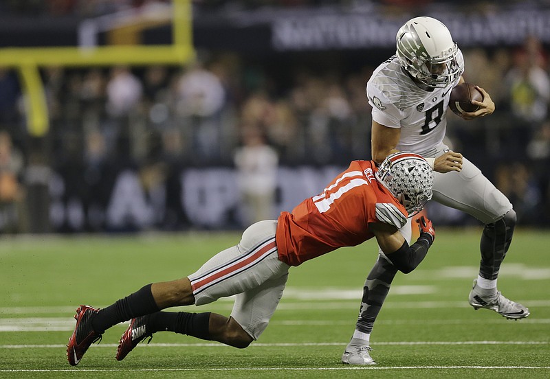 Oregon quarterback Marcus Mariota (8) is tackled by Ohio State defensive back Vonn Bell (11) in the NCAA college football playoff championship game Monday.