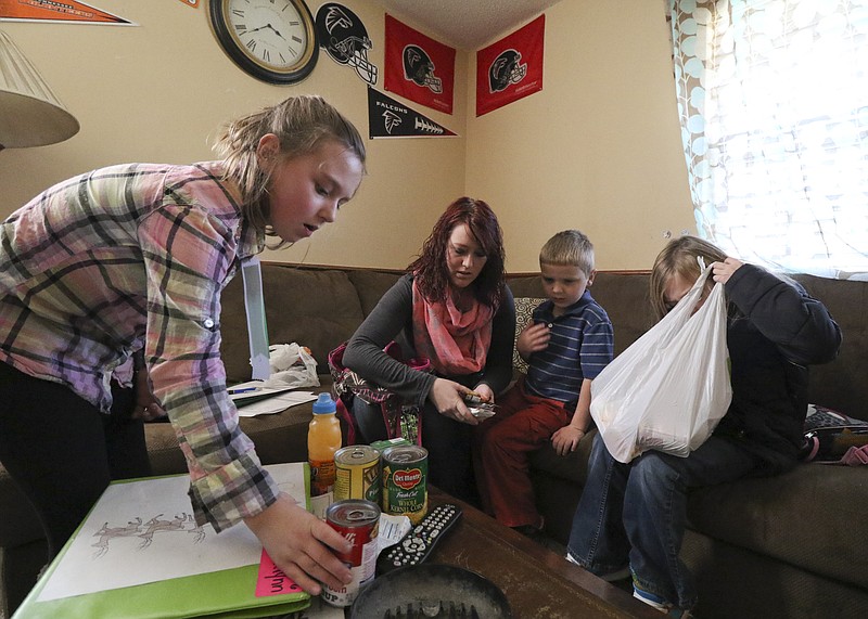 Katrina Gilbert, center, sorts through food that her children brought home from school while in the living room of their Ooltewah residence. Gilbert and her family starred in the HBO documentary "Paycheck to Paycheck: The Life and Times of Katrina Gilbert," which attempted to tell the story of the nation's impoverished women. The children are, from left, Brooklynn Gilbert, 9; Trent Gilbert, 5; and Lydia Gilbert, 7.