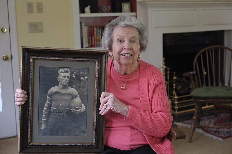 Jane Harper wears her father Lee Tolley's good-luck football charm, given to him after he lead Sewanee to an upset victory over Vanderbilt in 1914, as she holds his portrait on Thursday at her home in Signal Mountain, Tenn.