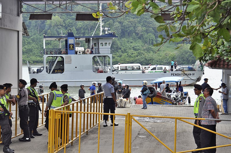 Police officers and security personnel stand guard as a ferry carrying ambulances sets off for Nusakambangan island where the executions of the five of six drug convicts are performed, at Wijayapura port in Cilacap, Central Java, Indonesia, on Jan. 17, 2015.