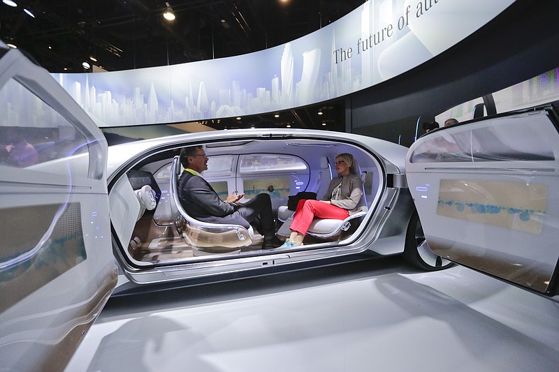 Attendees sit in the self-driving Mercedes-Benz F 015 concept car at the Mercedes-Benz booth at the International CES Tuesday, Jan. 6, 2015, in Las Vegas. 