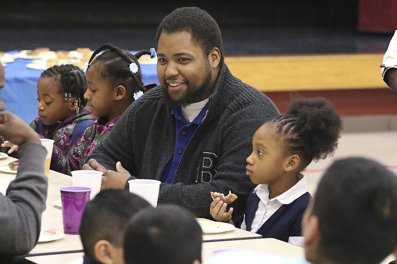 Stephen Brann, center, sits with his daughter Kimora Doyle, right, and other students during a "Donuts for Dads" gathering at Hardy Elementary on Tuesday. The gathering was held to encourage male role models to participate in their children's education. 