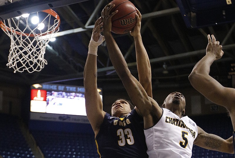 UTC forward Justin Tuoyo (5) and UNCG guard RJ White try to rebound the ball during the Mocs' SoCon basketball game against the UNCG Spartans on Saturday, Jan. 24, 2015, at McKenzie Arena in Chattanooga.