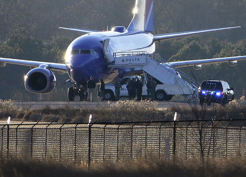 Law enforcement officials stand beneath a Southwest Airlines airplane on the tarmac at Hartsfield-Jackson Atlanta International Airport, Saturday, Jan. 24, 2015, in Atlanta.