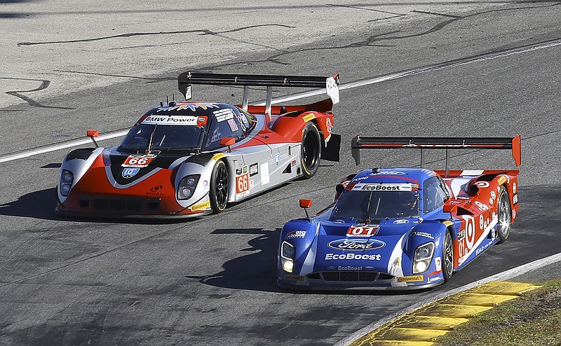 Race leader Scott Dixon (01) passes Shane Lewis through a turn early in the IMSA 24-hour race at Daytona International Speedway on Saturday.