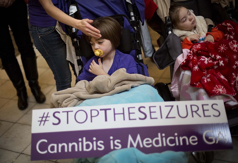 Rebecca Spinelli touches the face of her daughter McKenzie, 4, who has mitochondrial disease, as she holds a sign reading "stop the seizures" at a press conference on House Bill 1 at the state Capitol Jan. 13 in Atlanta.