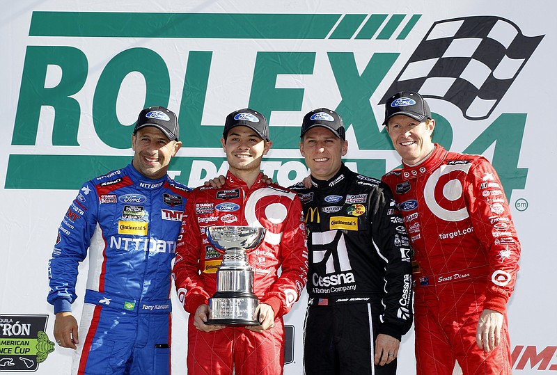 Winning drivers of the IMSA 24 hour auto race, from left, Tony Kanaan, of Brazil, Kyle Larson, Jamie McMurray and Scott Dixon, of New Zealand, pose for a photo with the first place trophy at Daytona International Speedway on Sunday, Jan. 25, 2015, in Daytona Beach, Fla.