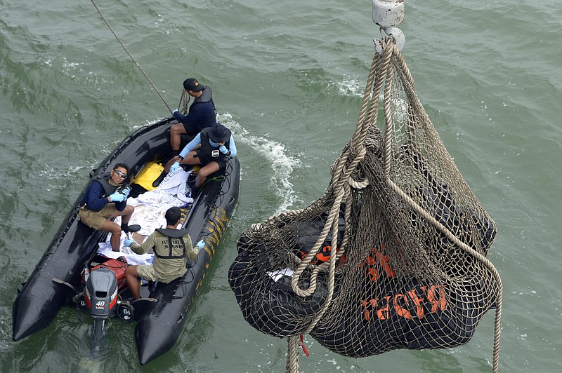 Bags containing dead bodies of the passengers of AirAsia Flight 8501 are lifted to Indonesian navy vessel KRI Banda Aceh at sea off the coast of Pangkalan Bun, Indonesia, Saturday, Jan. 3, 2015.
