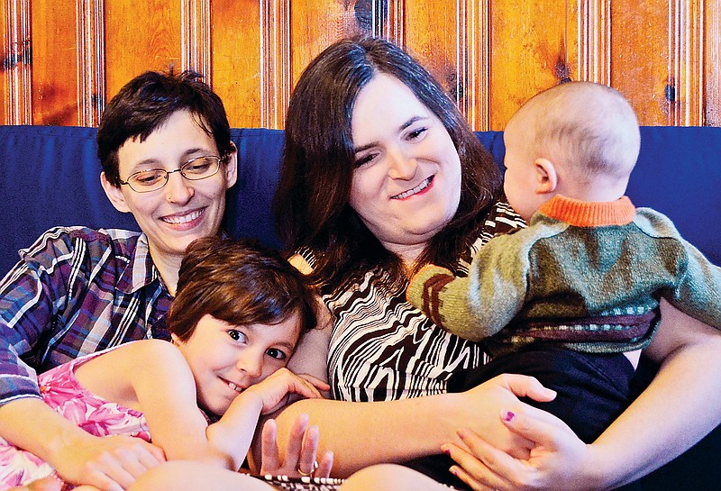 Meredith Russo, right, sits with her family, Juniper Russo, left, and children Vivian and Darwin in her East Lake home.