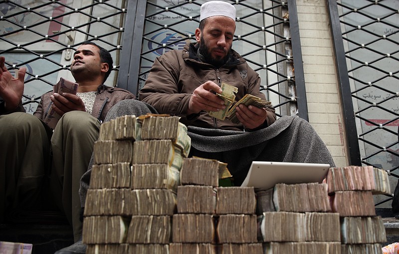 
              FILE - In this Monday, Jan. 12, 2015 file photo, An Afghan money changer, right, counts a pile of currency at the Money and Exchange Market in Kabul. Afghanistan’s fragile economy has lost around a third of its value in the past year as the international military and aid organizations that poured in cash for more than a decade have drastically scaled back after U.S. President Barack Obama declared an end to the 13-year war against the Taliban _ leaving the government struggling for funds and key sectors lacking investment, economists, analysts and officials said. (AP Photo/Massoud Hossaini, FIle)
            