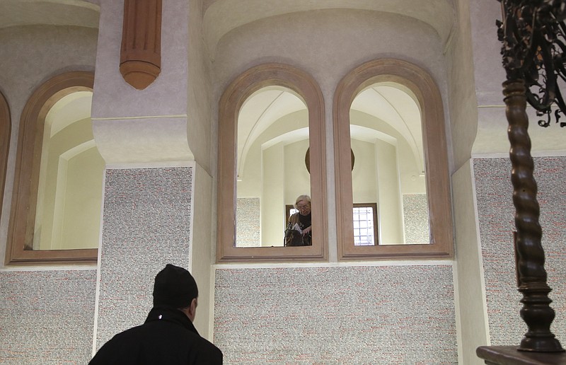 In this picture taken in Prague, Czech Republic, Wednesday, Jan. 21, 2015, tourist reads names of holocaust victims written on the walls of Pinkas Synagogue.